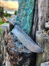 Damascus knife on a rustic wooden background with a sunset in the background