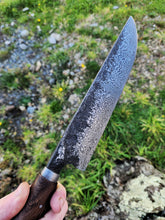 Benjamin holding a Damascus steel knife in his hand with a natural background