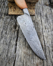 Railway wrought iron clad Damascus blade knife close-up with a wooden handle on a rustic wooden surface