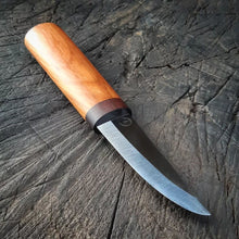 Puukko knife with two woods in the handle, the steel catches the light, showing off the pristine blade edge, on a textured wood surface.