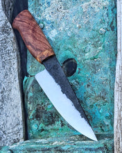 Hand forged knife with a wooden handle on a textured surface