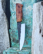 Hand forged knife with wooden handle on a patinaed copper surface. 