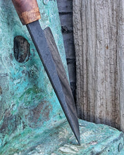 Close up of the hand forged blades mirror finish reflecting a textured wooden surface