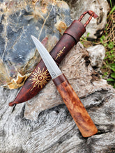 Puukko knife with wooden handle and leather sheath on a natural textural background