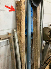 Stack of wrought iron rails salvaged from Bridge 189 with a red arrow pointing to the actual piece of railway iron used in the knife, set against a wall.