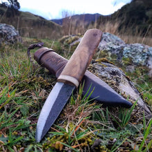 Homestead Puukko knife and its custom leather sheath in a grassy paddock