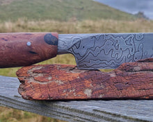 Off Track Machete integral bolster detail with kanuka handle and Damascus steel on a totara display stand, Mount Bruce farmland behind