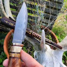 Storm Hunting knife with decorative handle and sheath against a natural background