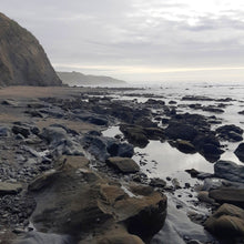 Riversdale Beach rocks and beach with a cliff and ocean in the background on a stormy grey day