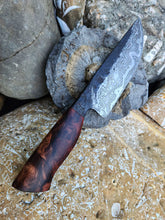 Decorative Damascus knife with a wooden handle on a stone surface
