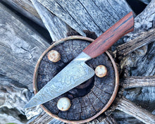 Wagon Wheel Chef Knife with a wooden wagon wheel spoke handle and a Damascus blade clad in wagon wheel wrought iron, photographed on a Victorian wagon wheel.