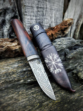 Puukko knife with decorative sheath on a wooden background