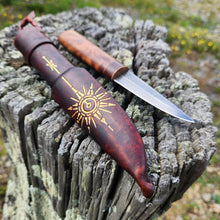 Puukko knife with wooden handle featuring star design on a textured totara tree stump surface