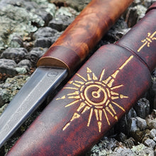 Close-up of a Puukko knife with a gold star compass design on a textured background