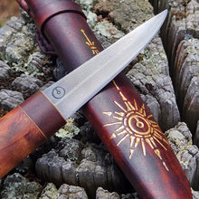 Damascus steel Puukko knife with wooden handle and embossed sheath on a textured background