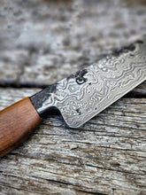 Damascus knife with Pohutukawa wood handle on a textured wooden surface