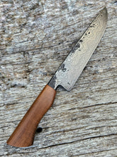 Damascus knife with a Pohutukawa wood handle on a textured wooden surface