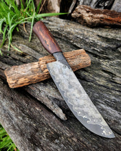Handcrafted knife with a wagon wheel wood handle resting on its wagon wheel display stand on a rustic wooden surface