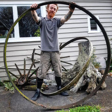 Benjamin holding a large victorian wrought iron wagon wheel from the historic Opaki Racecourse.