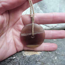 Disc Pendant carved from New Zealand Fossilized Wood, held in Marisa's hand to show scale.