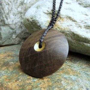 Sun and Moon Disc Pendant carved from New Zealand Fossilized Wood. This side of the disc has been gilded with gold leaf.