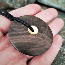 Sun and Moon Disc Pendant carved from New Zealand Fossilized Wood held in Marisa's hand showing the size of the piece.