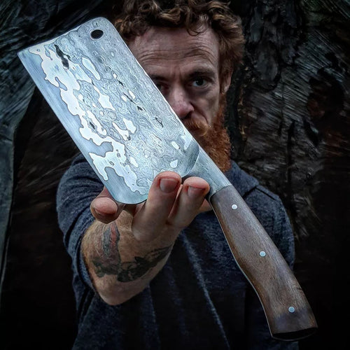 Wrought iron clad integral meat cleaver with a Pohutukawa handle in hand of the maker, Benjamin Madden.